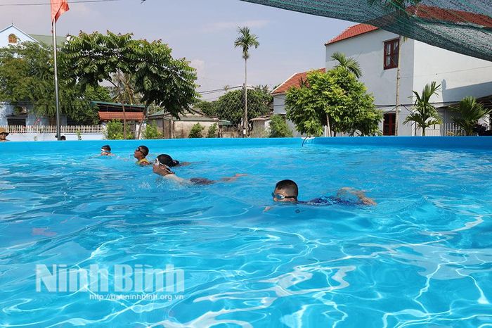 Các em thiếu nhi được hướng dẫn và thực hành kỹ năng bơi ếch tại bể bơi.