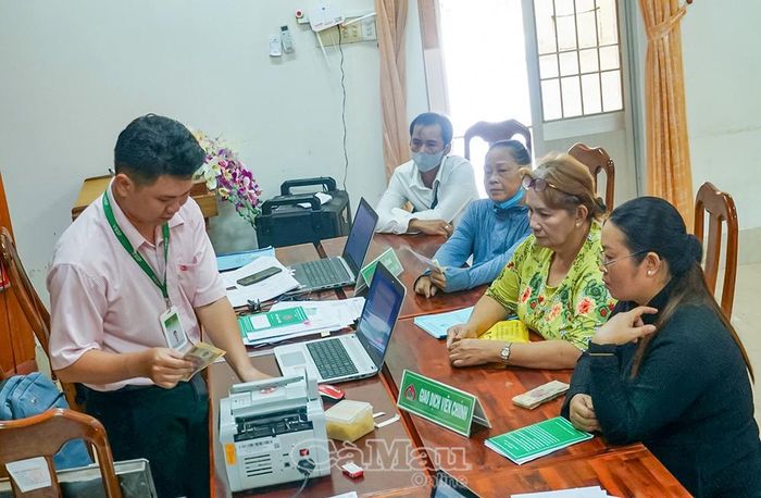 Cán bộ Phòng Giao dịch NHCSXH Đầm Dơi giải ngân vốn vay ưu đãi cho các hộ dân tại Xã Trần Phán.