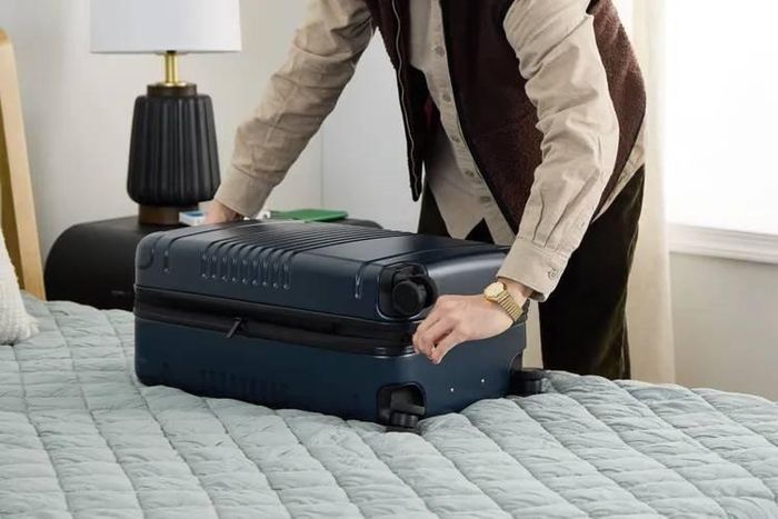  Một du khách mở vali trên giường trong phòng khách sạn. Ảnh: Travel + Leisure. 