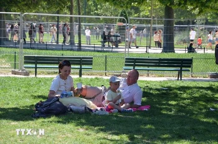 Một gia đình tránh nóng dưới bóng mát trong một công viên ở thủ đô Paris. Ảnh: TTXVN