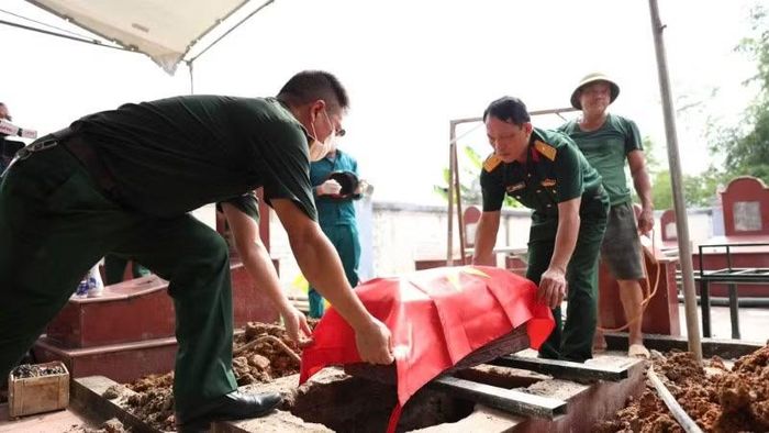 Phủ cờ Tổ quốc cho một phần hài cốt liệt sĩ tại Nghĩa trang liệt sĩ Đu-Động Đạt, xã Phú Lương.