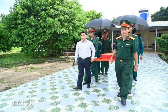 Thủ trưởng Bộ Chỉ huy quân sự tỉnh Cà Mau và lãnh đạo xã Trần Văn Thời cùng các chiến sỹ di chuyển các mẫu sinh phẩm hài cốt liệt sỹ đi giám định ADN ra xe chuyên dụng. (Ảnh: Văn Đông/TTXVN phát)