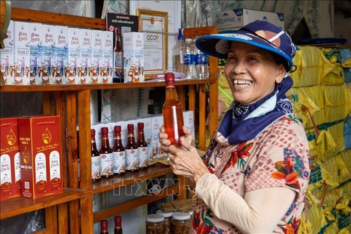 Bà Phan Thị Ngọc Bích, chủ cơ sở sản xuất nước mắm Hương Làng Cổ, giới thiệu mắm ruốc với một người hàng xóm. Theo bà, dù sẵn sàng thử nghiệm sản phẩm mới, nước mắm cá cơm truyền thống vẫn là hương vị đặc trưng của Nam Ô.