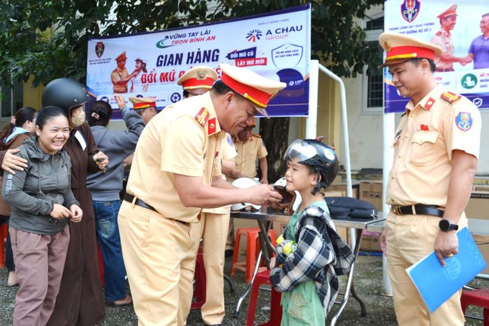 Đại tá Phan Thanh Hồng (bên trái), Trưởng phòng Cảnh sát giao thông trò chuyện với một em nhỏ về sự cần thiết phải đội mũ bảo hiểm. Ảnh: CÔNG TÚ