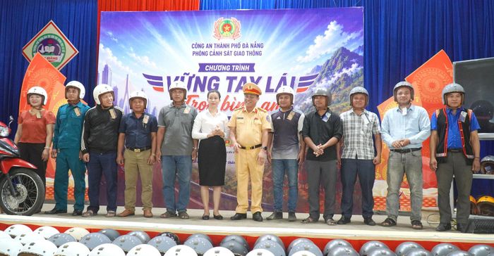 Lãnh đạo Phòng Cảnh sát giao thông và UBND xã Bến Giằng tặng mũ bảo hiểm cho đại diện các thôn trên địa bàn. Ảnh: CÔNG TÚ
