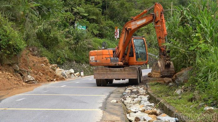Máy xúc thu dọn đất, đá sạt lở ven đường, góp phần bảo đảm tuyến giao thông thông suốt.