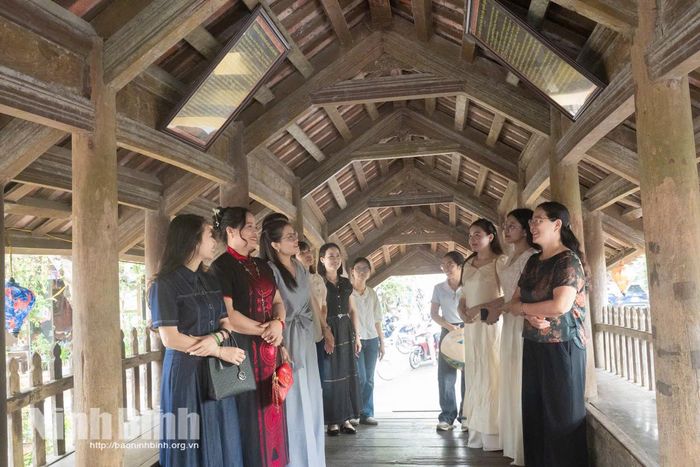 Đại diện Hiệp hội Du lịch tỉnh Ninh Bình cùng du khách nghe giới thiệu về kỹ thuật gia công mộc mạc bằng phương pháp mộng khít độc đáo bên trong lòng Cầu ngói chợ Lương. Ảnh: Ngọc Linh