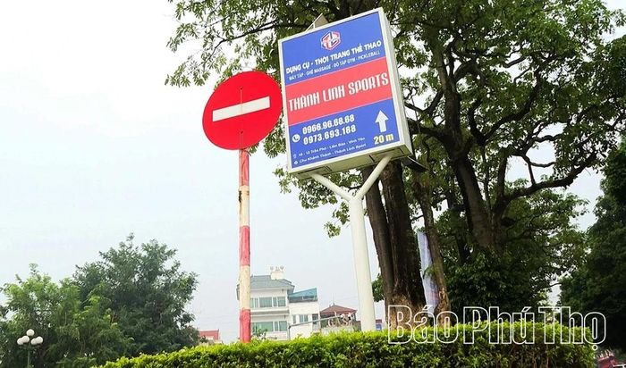 Biển quảng cáo ngoài trời xuất hiện sát biển báo giao thông tại nút giao giữa đường Mê Linh và đường Trần Phú, phường Vĩnh Phúc, ảnh hưởng đến mỹ quan đô thị.