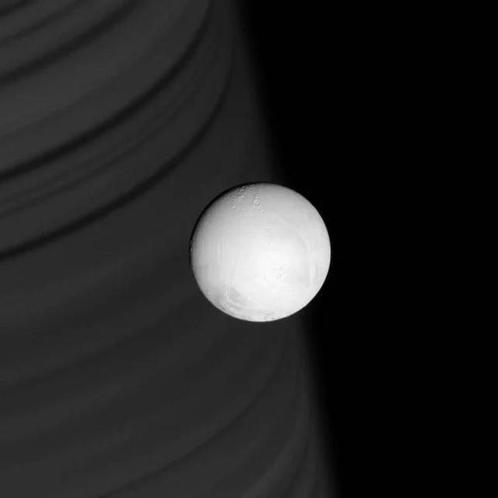Hình ảnh Enceladus do tàu Cassini chụp năm 2007. Ở phía xa, bóng của các vành đai tạo thành những vệt trên bầu khí quyển của Sao Thổ. Ảnh: NASA