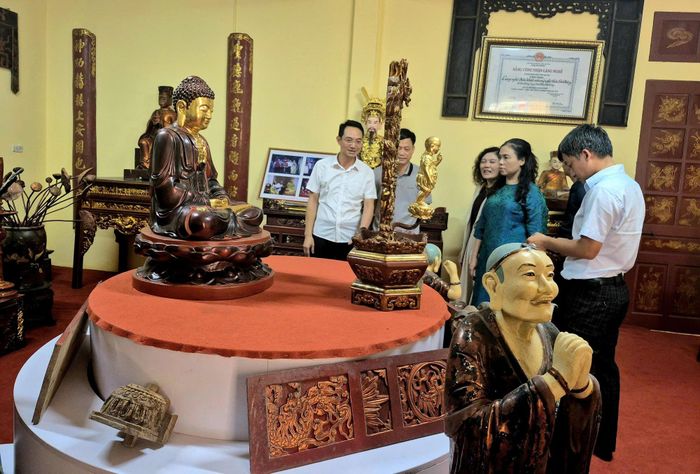Ông Cao Văn Tâm, Phó Chủ tịch UBND xã Sơn Đồng (đeo kính) giới thiệu các sản phẩm của làng nghề Sơn Đồng. Ảnh: Thiện Tâm