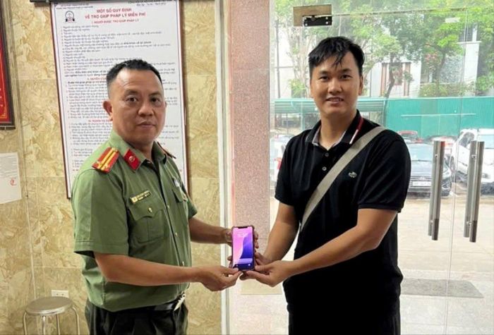 Cán bộ Tổ An ninh Công an phường Phú Thượng tiếp nhận chiếc điện thoại do anh Đoàn Văn Bách giao nộp để hỗ trợ tìm chủ sở hữu. Ảnh: PT