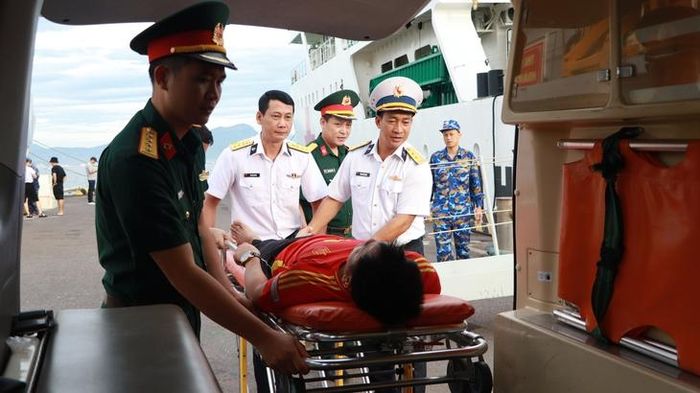 Vận chuyển ngư dân từ tàu 571 lên xe cứu thương để bác sĩ Đội Điều trị 486 kiểm tra sức khỏe, đánh giá tình trạng ổn định trước khi bàn giao.