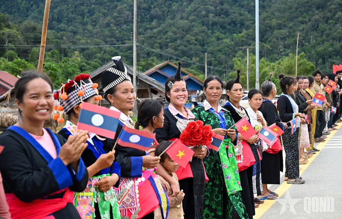 Nhân dân địa phương đứng bên đường chào đón đoàn đại biểu hai nước đến thăm Trường Tiểu học Thongnammoun.