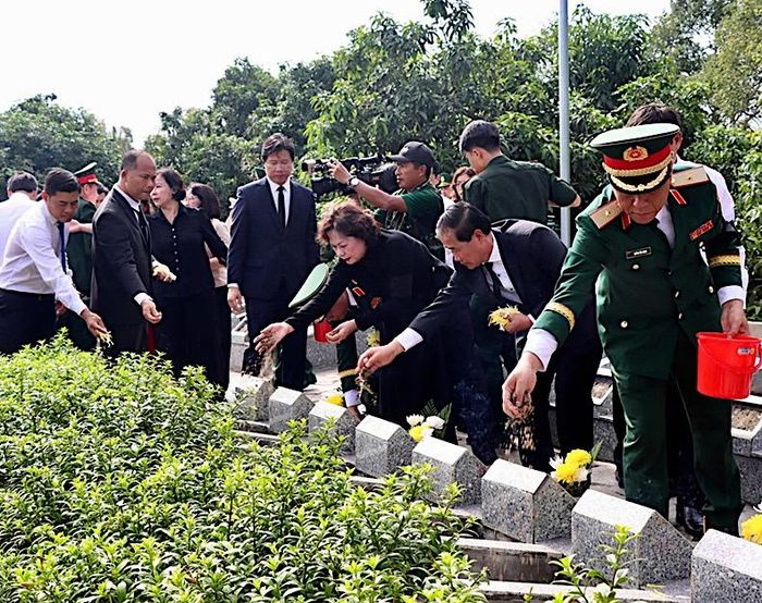 Các đại biểu thành kính gửi những nắm đất và hoa lên phần mộ các liệt sĩ