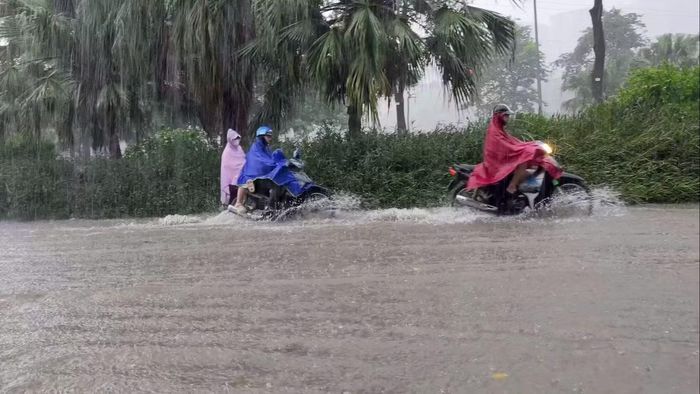  Người điều khiển xe máy giảm tốc độ khi lưu thông qua khu vực ngập nước. 
