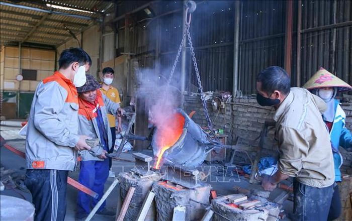 Các công nhân đổ đồng được nấu chảy ở nhiệt độ cao vào khuôn đúc.