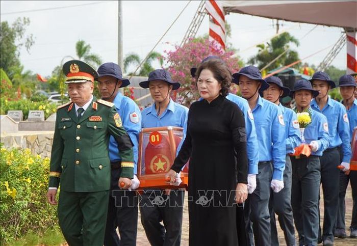 Các đại biểu thực hiện nghi thức đưa hài cốt liệt sĩ đến nơi an nghỉ. Ảnh: Nhựt An/TTXVN.