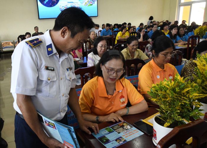 Phát tờ rơi, hướng dẫn ngư dân chấp hành Luật Thủy sản trong quá trình khai thác trên biển. Ảnh: Thành Định