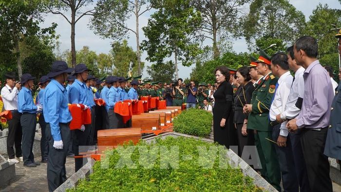 Các đại biểu thực hiện nghi thức đưa hài cốt liệt sỹ đến nơi an nghỉ. Ảnh: Nhựt An - TTXVN