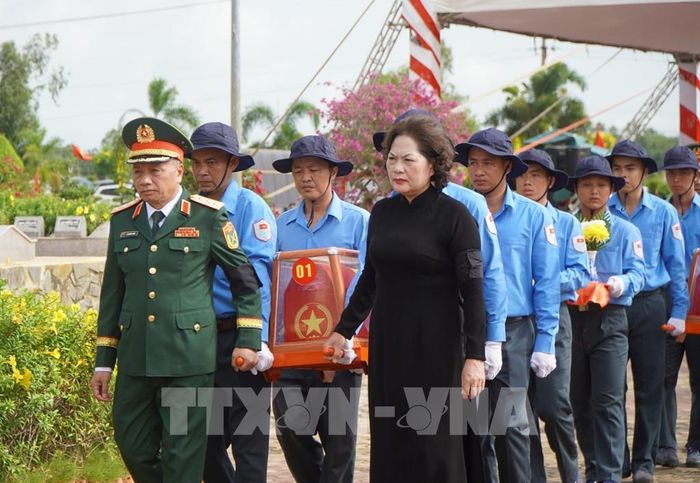 Các đại biểu thực hiện nghi thức đưa hài cốt liệt sĩ đến nơi an nghỉ. Ảnh: Nhựt An - TTXVN