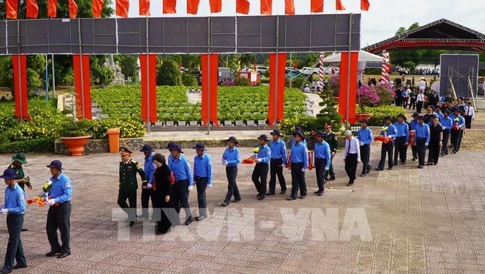Các đại biểu thực hiện nghi thức đưa hài cốt liệt sĩ đến nơi an nghỉ. Ảnh: Nhựt An - TTXVN