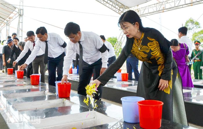 Đại biểu đặt nắm đất, rải hoa xuống phần mộ tiễn đưa các liệt sĩ.