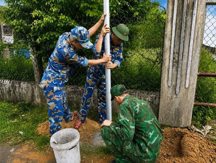 Bộ đội đào hố lắp đặt trụ đèn năng lượng mặt trời tại làng Vĩnh An. Ảnh: Khoa Đoàn