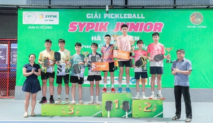 Hai vận động viên Trần Gia Bảo và Nguyễn Hải Nam chụp ảnh cùng các vận động viên đạt thành tích cao ở nội dung đôi nam U15 tại Giải Pickleball Junior Hà Tĩnh Open 2026.
