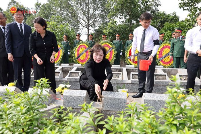 Phó Chủ tịch Quốc hội Nguyễn Thị Hồng rải những nắm cát đầu tiên xuống mộ phần liệt sĩ
