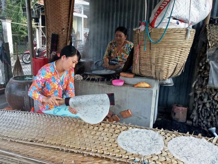  Nghệ nhân tráng bánh đang thực hiện công đoạn tráng bánh trên khuôn vải, thể hiện kỹ thuật thủ công truyền thống. 