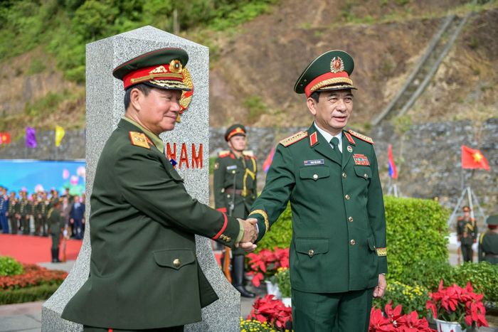 Bộ trưởng Bộ Quốc phòng Việt Nam và Lào chụp ảnh lưu niệm tại cột mốc biên giới. Ảnh: Nam Trần