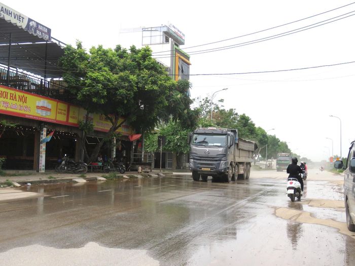 Nhiều hộ dân sống quanh dự án tự xả nước khắc phục tình trạng bụi, cát do xe chở vật liệu đi qua. Ảnh: Hy Ninh