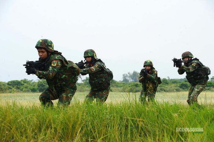 Từng tổ chiến đấu cơ động qua khu vực trống, giữ đội hình và quan sát mục tiêu phía trước.