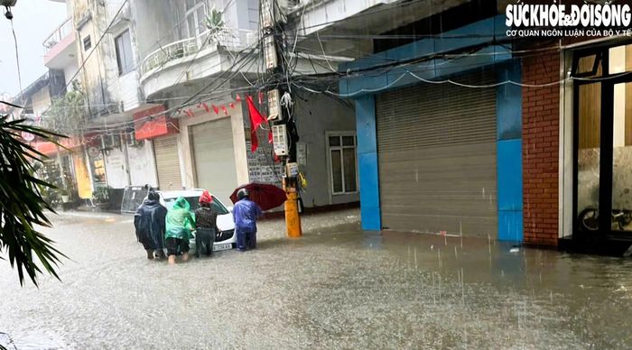 Phương tiện đang đi bị nước ngập gây chết máy được người dân hỗ trợ di chuyển ra khỏi chỗ sâu. Ảnh: CTV