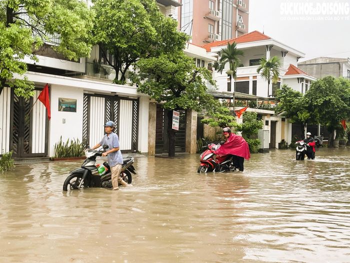 Khu vực gần chợ Lũng lụt sâu, xe chết máy giữa đường khiến người dân phải dắt bộ qua đoạn lụt. Ảnh: T.Dung