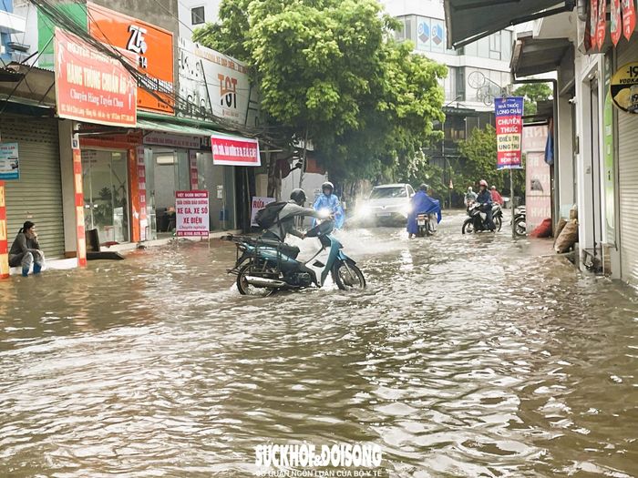 Người dân vật lộn khi di chuyển qua khu vực ngập lụt.