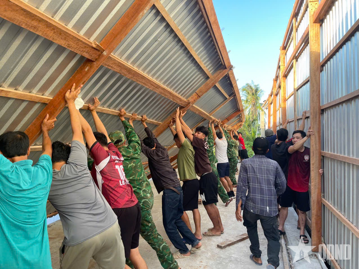 Cán bộ, chiến sĩ Đồn Biên phòng Đất Mũi cùng người dân dựng lại nhà cho gia đình chị Nguyễn Như Quỳnh.