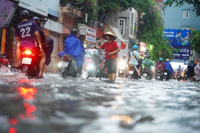 Tại phố Hoàng Văn Thái, nước dâng quá nửa bánh xe máy. Người điều khiển phương tiện di chuyển chậm.