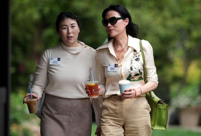 Doanh nhân Đặng Văn Địch (phải) - vợ cũ Rupert Murdoch, trùm truyền thông, Chủ tịch kiêm Tổng giám đốc tập đoàn News Corporation - diện sơ mi lụa màu kem phối quần âu cạp cao cùng tông, ưu tiên bảng màu trung tính. Chiếc túi xách màu xanh lá trở thành điểm nhấn của bộ trang phục.
