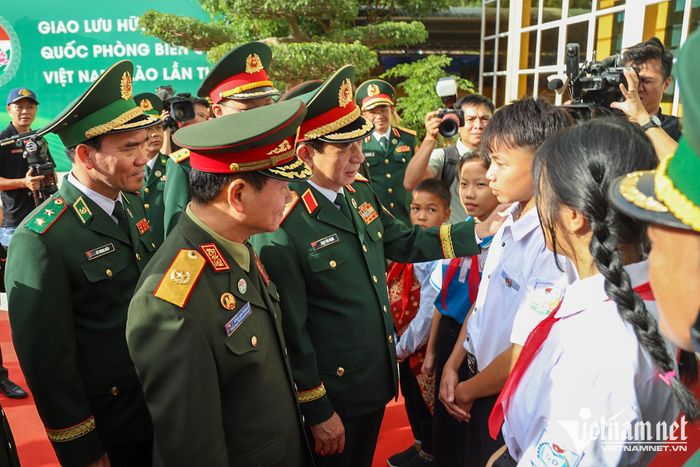 Hai lãnh đạo trò chuyện với các em học sinh trong chương trình "Nâng bước em tới trường - Con nuôi đồn biên phòng" - nhận nuôi dưỡng các học sinh có hoàn cảnh đặc biệt khó khăn (bao gồm cả trẻ em Lào)