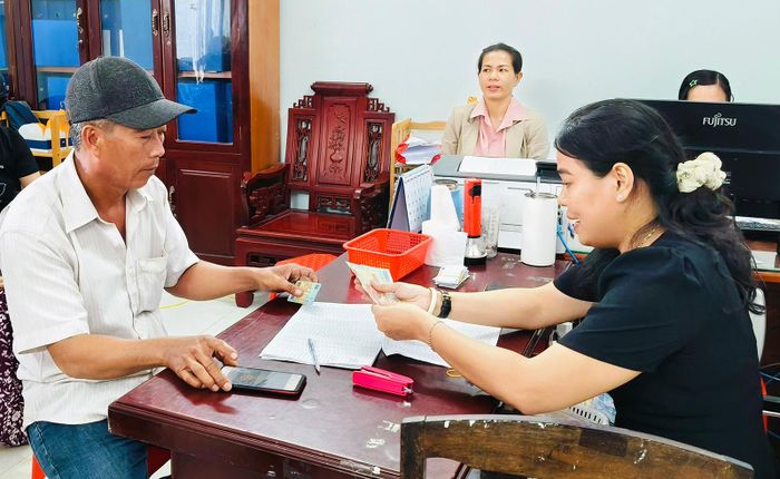 Cán bộ Bảo hiểm xã hội cơ sở An Biên thực hiện chi trả tiền hoàn Bảo hiểm y tế cho người dân.
