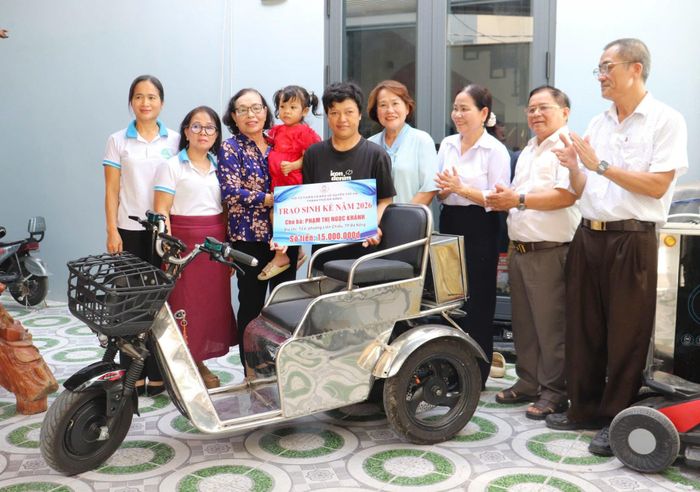 Hội Từ thiện và Bảo vệ quyền trẻ em thành phố tặng xe điện 3 bánh cho chị Phạm Thị Ngọc Khánh (thứ 5, bên trái sang). Ảnh: ĐVCC