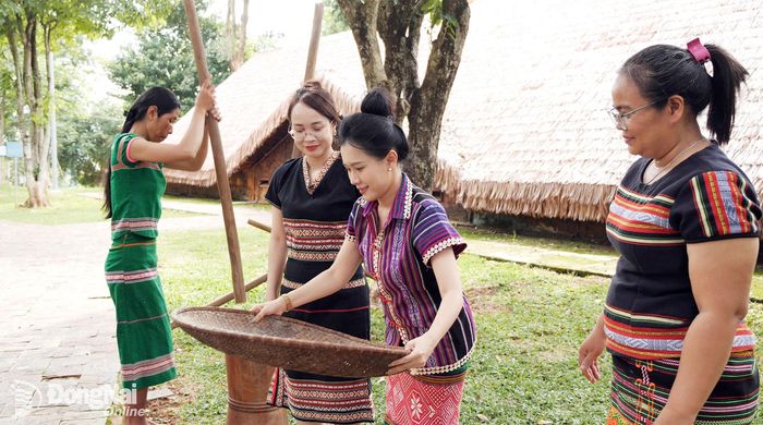 Chị Điểu Thị Xia cùng người dân địa phương hướng dẫn hai MC Diệu Hiền và Minh Tuyết sàng gạo theo tập quán truyền thống. Ảnh: Tiến Dũng