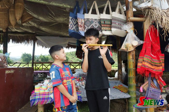 Các em nhỏ trải nghiệm thổi sáo tại gian hàng bán đồ thổ cẩm chợ phiên bản Vặt Hồng.