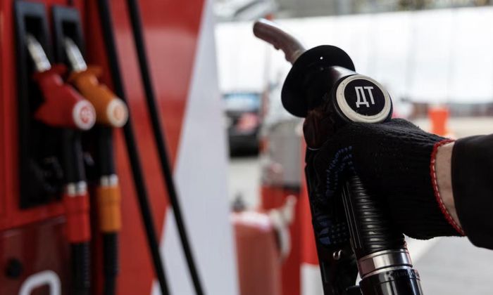 Một nhân viên cầm vòi bơm nhiên liệu diesel tại trạm xăng của công ty Neftmagistral ở Moscow, Nga - Ảnh: Reuters