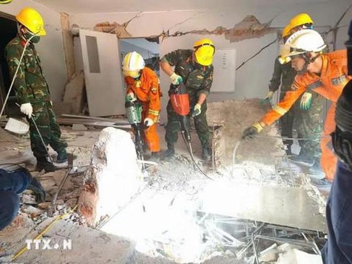 Các đội cứu hộ Việt Nam, Myanmar và UAE đục bê - tông để mở lối tiếp cận vị trí các nạn nhân bị vùi lấp ở Myanmar. Ảnh: TTXVN