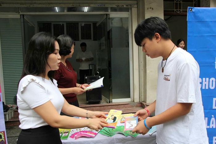 Nhân viên y tế cấp phát tờ rơi tuyên truyền về công tác dân số cho trẻ vị thành niên. Ảnh: PV