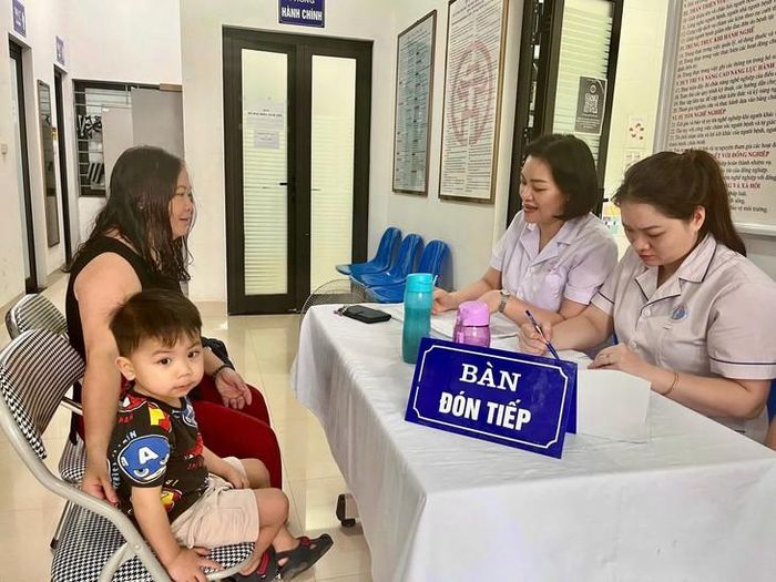 Phụ huynh đưa trẻ làm thủ tục đăng ký khám tại Trạm Y tế phường Phương Liệt.