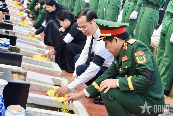 Các đại biểu kính cẩn thả những nắm đất và cánh hoa đầu tiên tiễn đưa các anh hùng liệt sĩ về với đất mẹ. 