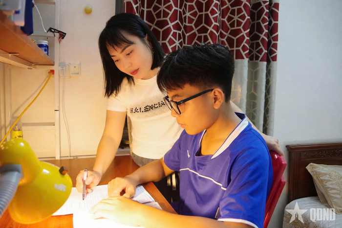 Đồng chí Nguyễn Thị Huệ hướng dẫn con học bài.